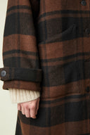 Patron Le Manteau – Détail manche et poche, manteau tartan brun/noir, manchette boutonnée, pull écru – Atelier Brunette