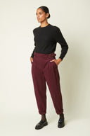 Belted Trousers pattern – Front view, trousers burgundy high waist with pleats, metal buckle belt, black jumper – Atelier Brunette