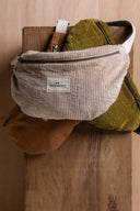 Bum Bag pattern – bum bag corduroy off-white, gold zip fastener, front view wood background – Atelier Brunette