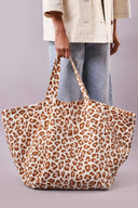 Patron Sac de plage – Sac oversize imprimé léopard blanc/caramel tenu à deux mains, fond lilas/mauve – Atelier Brunette