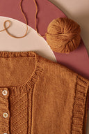 Patron tricot Le Pull et le Gilet – gilet tricoté moutarde à plat avec pelote de laine, fond rose – Atelier Brunette