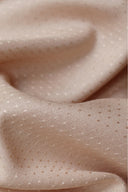 Gros plan macro sur un tissu viscose plumetis rose blush pâle, plié en vagues, laissant voir la texture à petits pois tissés.