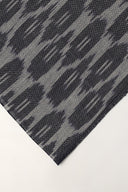 Close-up of the folded corner of the anthracite voile, showing the abstract ikat-style pattern and the frayed selvedge.