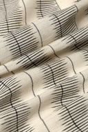 L'Ikat fabric in off-white with fine anthracite ikat-style stripes, draped in diagonal folds.