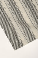 Close-up of the folded corner of the off-white fabric, showing the anthracite plumetis-style stripes and the frayed selvedge.