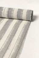 Off-white fabric rolled up, showing the anthracite ikat-style stripes along its full length.