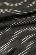L'Ikat fabric in anthracite with fine diagonal off-white ikat-style stripes, draped in tight folds.