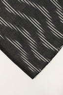 Close-up of the folded corner of the anthracite fabric, showing the diagonal off-white ikat-style stripes and the frayed selvedge.