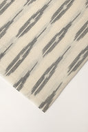 Close-up of the folded corner of the off-white fabric, showing the anthracite plumetis-style stripes and the frayed selvedge.