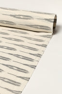 Off-white fabric rolled up, showing the anthracite ikat-style stripes along its full length.