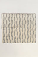 L'Ikat fabric in off-white folded flat, with anthracite ikat-style stripes arranged in regular bands across the whole piece.