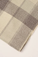 Le Carreau 006 ecru fabric with tartan-style mottled taupe checks, rolled up showing the woven selvedge.