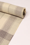 Close-up of the corner of the Le Carreau 006 ecru fabric with tartan-style mottled taupe checks, highlighting the pattern and the frayed selvedge.