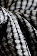 Tissu seersucker anthracite et écru à petits carreaux vichy, drapé en plis fluides laissant apparaître la texture gaufrée caractéristique du seersucker.