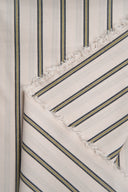 Tissu Weave Line écru à fines rayures gris-bleu et moutarde, plié en pointe avec sa lisière frangée apparente.